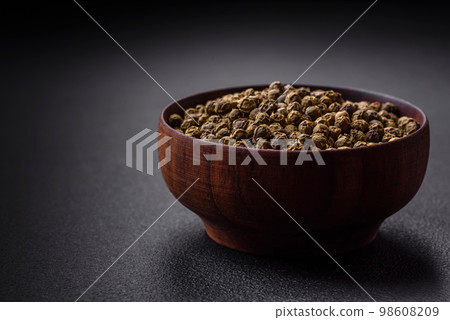 Spice, allspice green in a wooden bowl on a black concrete background 98608209