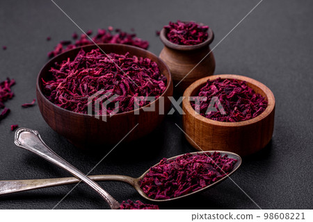 Dried beets in small slices in a wooden bowl on a black concrete background 98608221