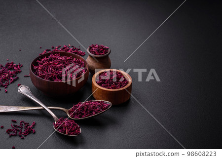 Dried beets in small slices in a wooden bowl on a black concrete background 98608223