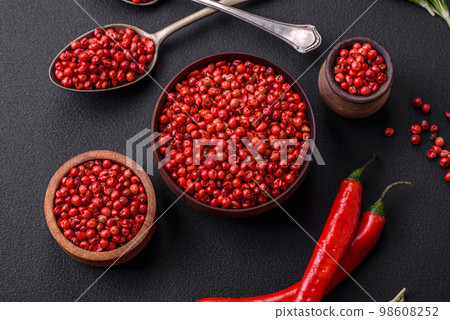 Spice, allspice peas of red or pink color in a wooden bowl 98608252
