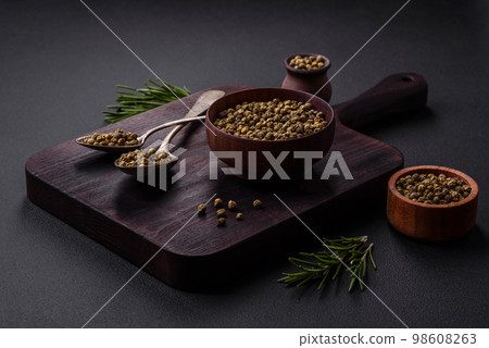 Spice, allspice green in a wooden bowl on a black concrete background Spice, allspice green in a wooden bowl on a black concrete background 98608263