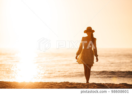 Young happy woman on the beach enjoy her summer vacation. Beautiful woman in hat is happy and calm in her stay on the beach Young happy woman on the beach enjoy her summer vacation. Beautiful woman in hat is happy and calm in her stay on the beach 98608601