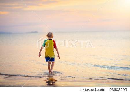 Child playing on ocean beach. Kid at sunset sea. Child playing on ocean beach. Kid at sunset sea. 98608905