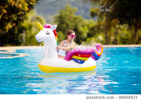 Child on unicorn float in swimming pool. Kids swim Child on unicorn float in swimming pool. Kids swim 98608925