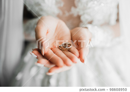 Beautiful luxury bride in elegant white dress holds wedding rings in the hands 98608950
