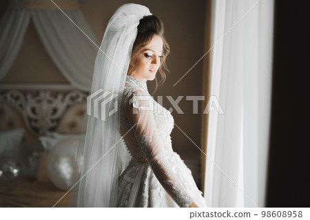 Beautiful bride wearing fashion wedding dress with feathers with luxury delight make-up and hairstyle, studio indoor photo shoot 98608958