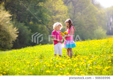 Kids play. Child in dandelion field. Summer flower Kids play. Child in dandelion field. Summer flower 98608996