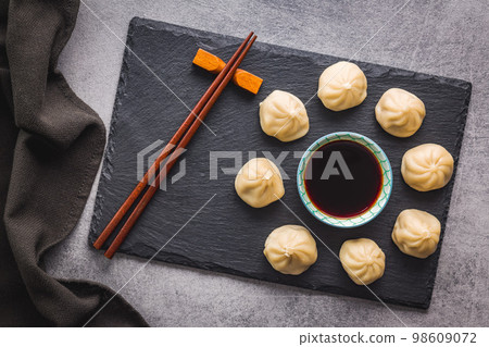 Xiaolongbao, traditional steamed dumplings and soy sauce. Xiao Long Bao buns on cutting board. Top view. 98609072