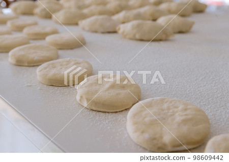 White countertop is used for preparing baking of buns with stuffing and donuts from yeast dough 98609442