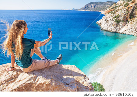 Young woman making selfie photo by smartphone over Kaputas beach 98610102