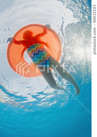 Underwater photo of girl swimming with fun on inflatable tube 98610105