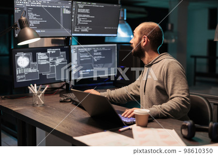 Software developer coding database on multiple monitors to program new server interface at night. Workign after hours to develop html source code on terminal window, artificial intelligence. Software developer coding database on multiple monitors to program new server interface at night. Workign after hours to develop html source code on terminal window, artificial intelligence. 98610350