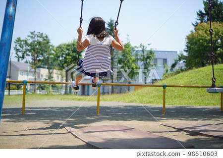Elementary school girl playing on a swing Elementary school girl playing on a swing 98610603