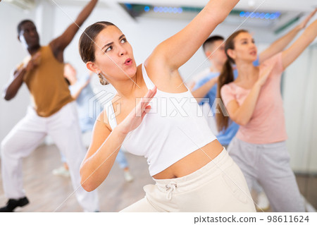 Group of sporty young adult multinational sports people making straight line with hands exercising dancing in gym Group of sporty young adult multinational sports people making straight line with hands exercising dancing in gym 98611624