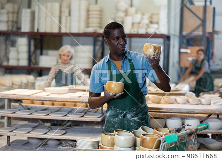 Man ceramist working in pottery workshop 98611668
