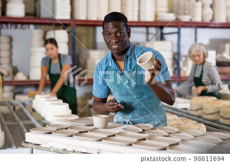 African american artisan having ceramics in hands and standing in workshop African american artisan having ceramics in hands and standing in workshop 98611694