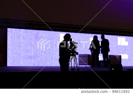 Black silhouettes of people - the cameraman records the interview on camera Black silhouettes of people - the cameraman records the interview on camera 98611891