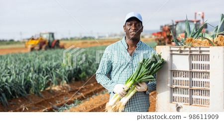African american man with a leek in hand in field 98611909