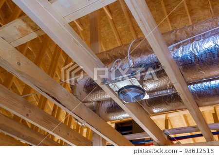 Ceiling inside new stick built home process of being built has ventilation pipes covered in silver insulation material Ceiling inside new stick built home process of being built has ventilation pipes covered in silver insulation material 98612518