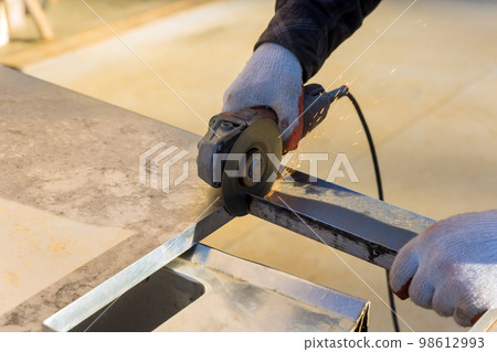 Metal is being cut by worker using with grinder as he works Metal is being cut by worker using with grinder as he works 98612993