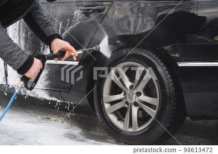 the car at the car wash is covered with foam, wash under pressure with a stream of water the car at the car wash is covered with foam, wash under pressure with a stream of water 98613472