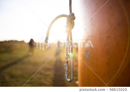 a rock climber's carabiner on a lanyard in a beautiful backlight 98615020