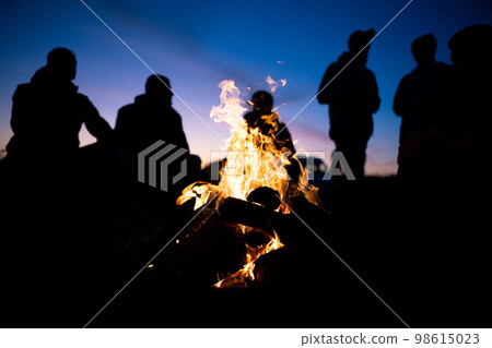 a group of friends gathered around the fire at night a group of friends gathered around the fire at night 98615023