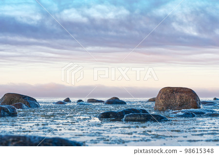 Panoramic view of the snow-covered shore of the Baltic sea at sunset. Ice fragments at sea close-up. Panoramic view of the snow-covered shore of the Baltic sea at sunset. Ice fragments at sea close-up. 98615348