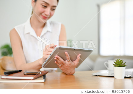 Beautiful millennial Asian woman using her digital tablet with stylus pen Beautiful millennial Asian woman using her digital tablet with stylus pen 98615706