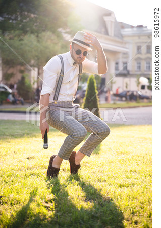 handsome presenter and showman in a stylish suit and hat with a microphone poses with the best emotions and acrobatic tricks handsome presenter and showman in a stylish suit and hat with a microphone poses with the best emotions and acrobatic tricks 98615972