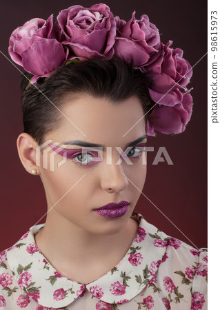 Close-up portrait girl with a pink lipstick and shadows for eyes and a wreath on his head Close-up portrait girl with a pink lipstick and shadows for eyes and a wreath on his head 98615973