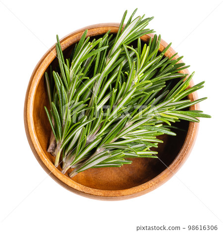 Fresh rosemary sprigs, in a wooden bowl. Rosemary twigs, branches of Salvia rosmarinus. Aromatic and evergreen shrub, with fragrant needle-like green leaves, used as a medicinal and culinary herb. 98616306