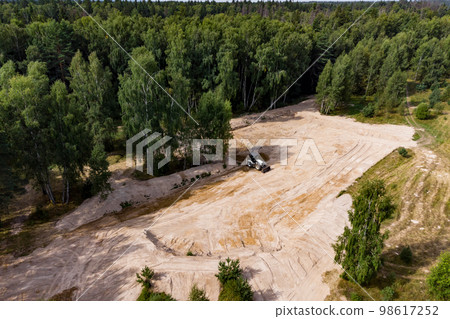 Removing the top layer of earth in the forest with a tractor before construction Removing the top layer of earth in the forest with a tractor before construction 98617252