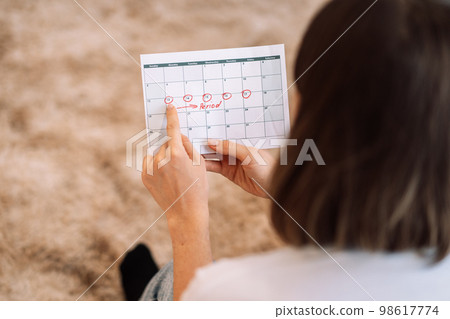 Lady looks at the days in the calendar menstrual cycle 98617774