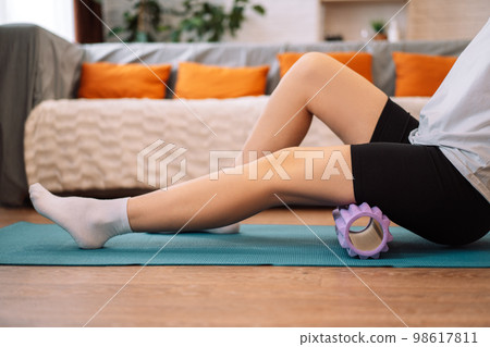 Lady massages herself with a purple massage roller Lady massages herself with a purple massage roller 98617811
