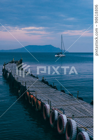 Old wooden fishing pier goes into the sea on sunset. Resort city Novyi Svet, Crimea Old wooden fishing pier goes into the sea on sunset. Resort city Novyi Svet, Crimea 98618806