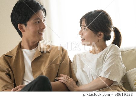 Cohabitation / newlywed image, smiling couple sitting on sofa Cohabitation / newlywed image, smiling couple sitting on sofa 98619158