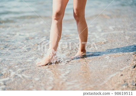 A woman walks along the beach, legs close-up. Barefoot woman sta A woman walks along the beach, legs close-up. Barefoot woman sta 98619511