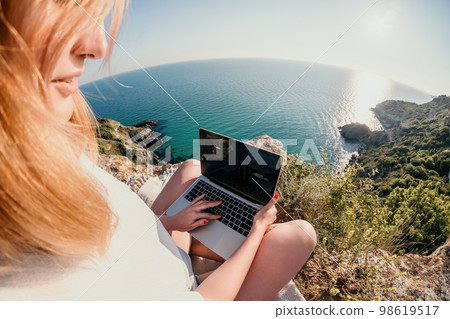 Woman sea laptop. Business woman working on laptop by sea at sunset. Close up on hands of pretty lady typing on computer outdoors summer day. Freelance, digital nomad, travel and holidays concept. 98619517