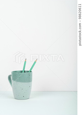 Coffee Cup Standing on Desk. Important infrormation written on paper. Different Office Supplies, Pencils, Pens, Marckers. Computer keyboard. Text on wood table. 98620611