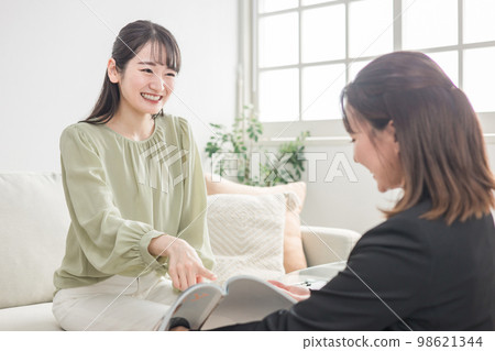 A business woman (Asian woman) who counsels with a woman who came to a meeting / consultation with a hair catalog / magazine 98621344