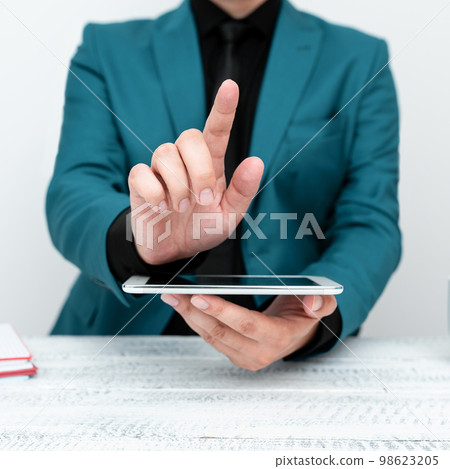 Businessman in Blue jacket sitting at table holding mobile phone And Pointing With One Finger On Important Message. Gentleman Showing Critical Announcement. 98623205