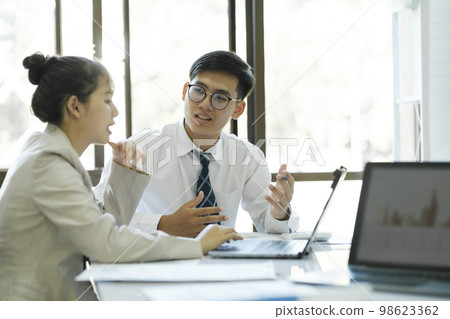 Businesspeople are working by disicuss and analyse their project by using laptop and calculator. 98623362