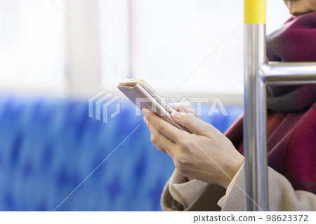 A woman's hand operating a smartphone on a train A woman's hand operating a smartphone on a train 98623372