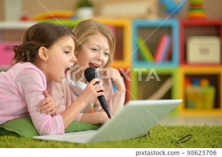 two little girls singing karaoke on laptop together 98623706