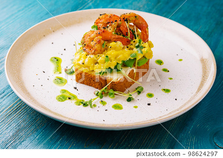 Scrambled eggs with avocado and shrimps on plate Scrambled eggs with avocado and shrimps on plate 98624297