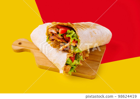 shawarma with chicken, tomatoes and lettuce on a wooden board 98624419