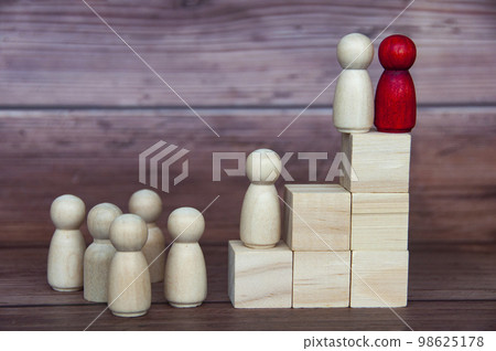 Leadership concept - two wooden figures on wooden blocks with other figures reaching to the top. Leadership concept. 98625178