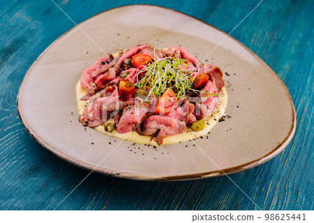 fried cured and sliced veal tongue with mashed potatoes 98625441