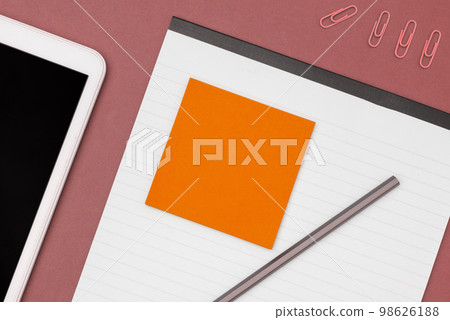 Mobile Phone Lying on Desk. Important infrormation written on colored paper and notebook. Different Office Supplies, Pencils, Pens, Marckers. Computer keyboard. 98626188